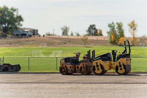Two street rollers sitting in the parking lot of Cahill Park